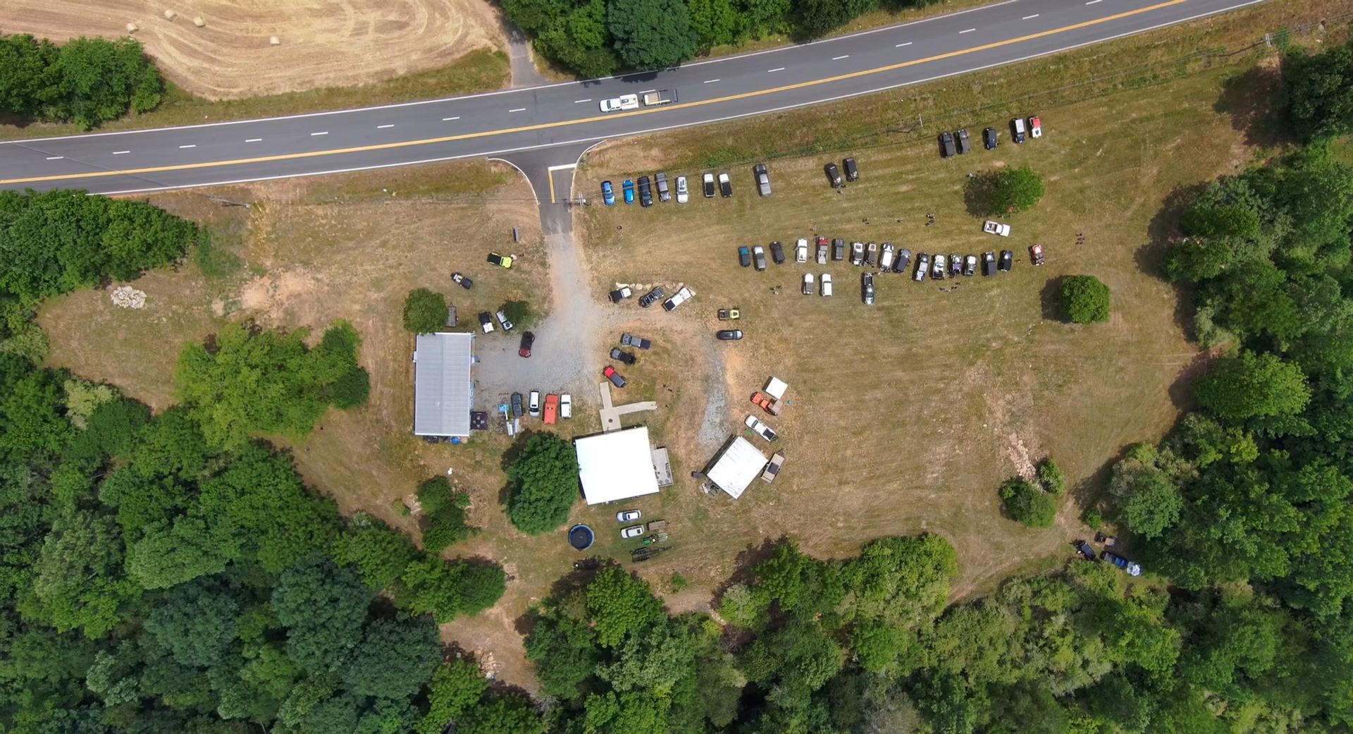An aerial view of a group of people standing in a field next to a road.