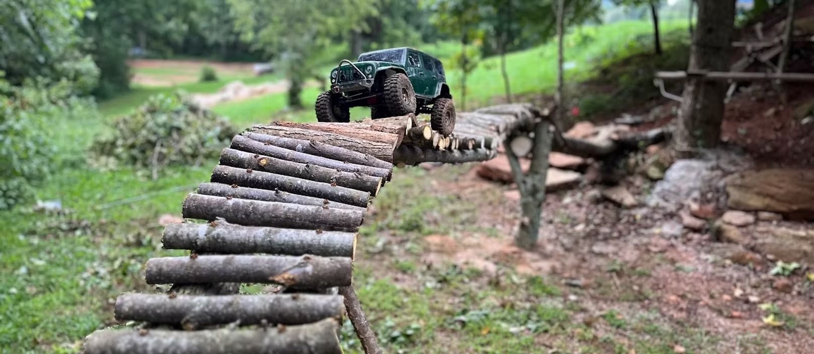A rc car is driving over a wooden bridge in the woods.