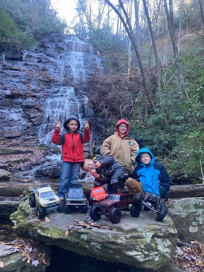 A group of children are posing for a picture in front of a waterfall.