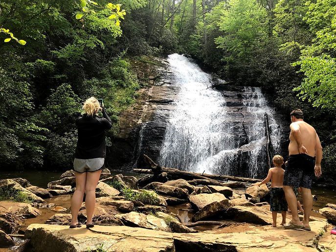 A group of people are standing in front of a waterfall.