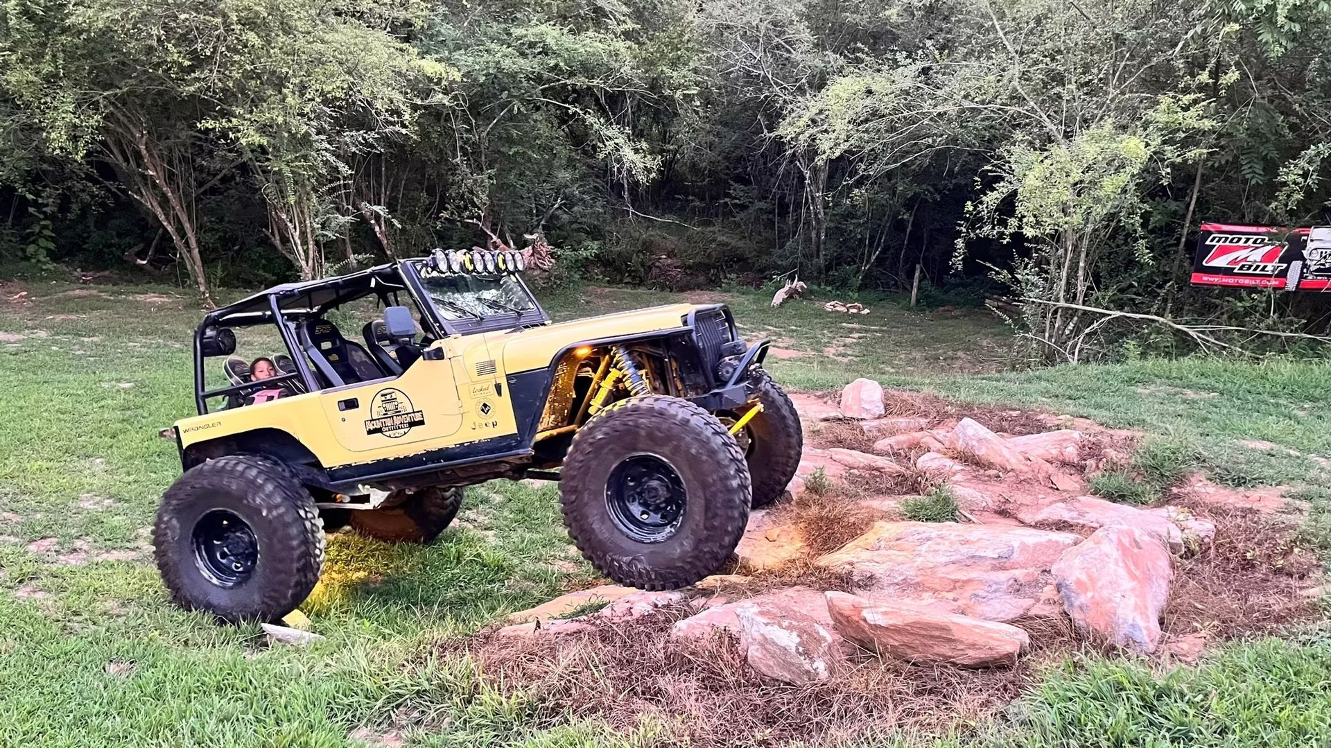 A yellow jeep is driving through a rocky area.