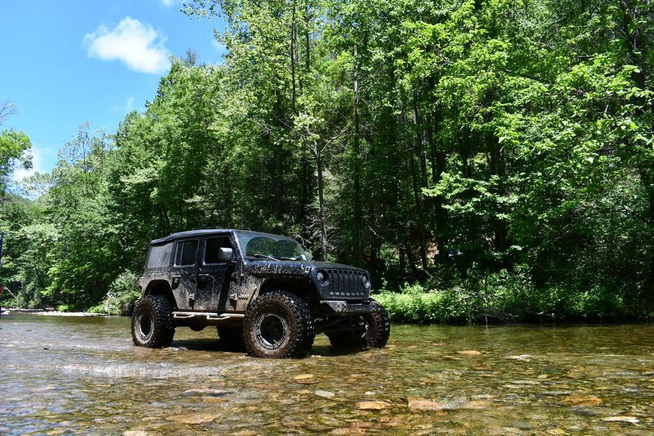 A group of people are standing in front of a waterfall in the woods.