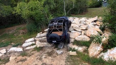 A black jeep is sitting on top of a rocky hill.