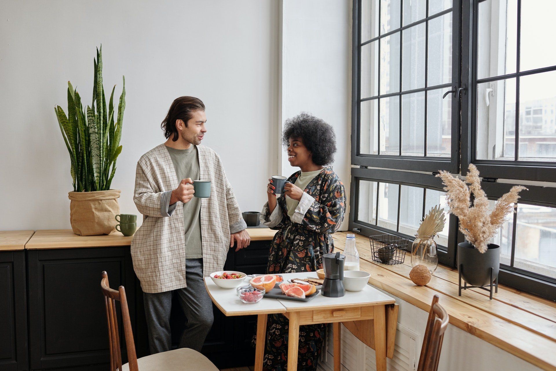 A man and a woman are sitting at a table drinking coffee.