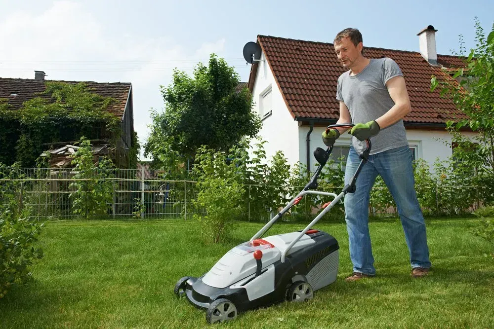 Man Mowing a Green Lawn With a Gray and Black Lawnmower — Garden City Slashing in Toowoomba, QLD