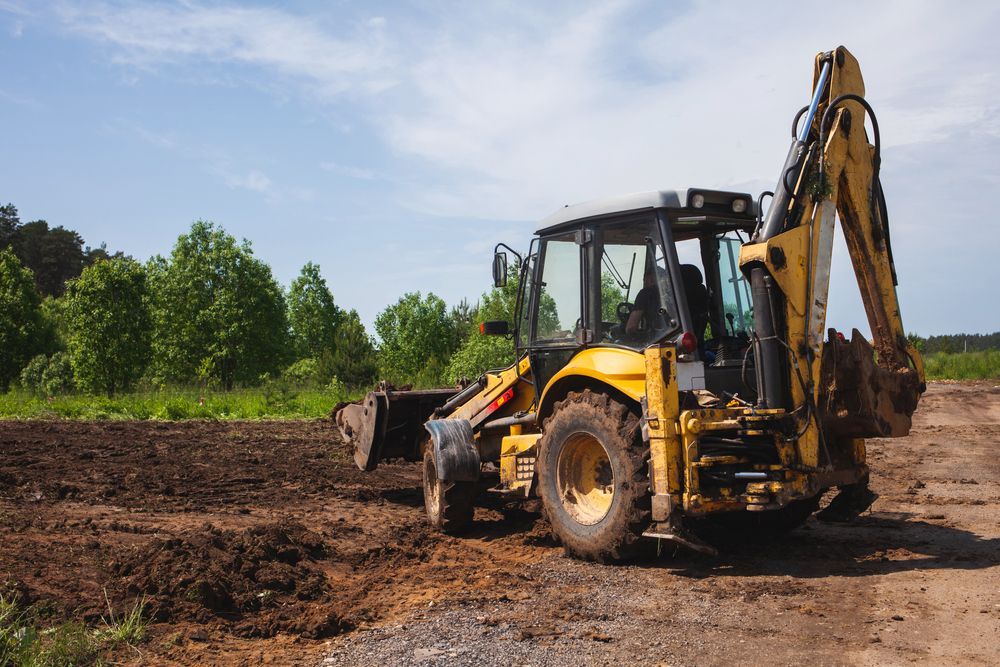 Yellow Backhoe on a Dirt Field With Trees in the Background — Garden City Slashing in Highfields, QLD