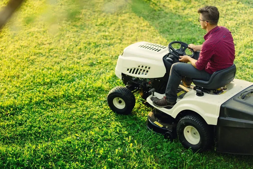 Man on a Riding Lawnmower Cutting Grass in a Sunny Yard — Garden City Slashing in Highfields, QLD