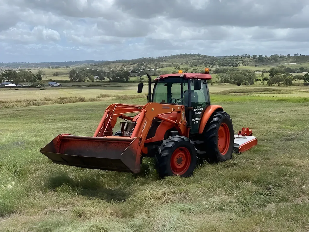 Orange Tractor With Front Loader in a Field Under Cloudy Sky — Garden City Slashing in Highfields, QLD
