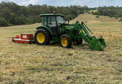 Green John Deere tractor with front loader and mower in a field— Garden City Slashing in Highfields, QLD