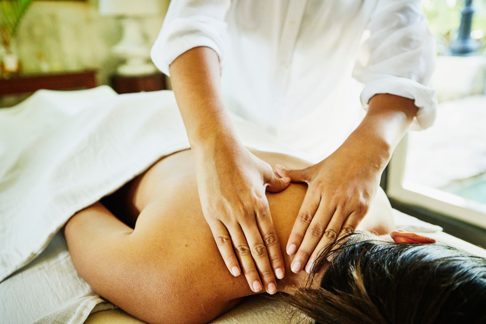 Person receiving a back massage in a spa setting, hands on their back.