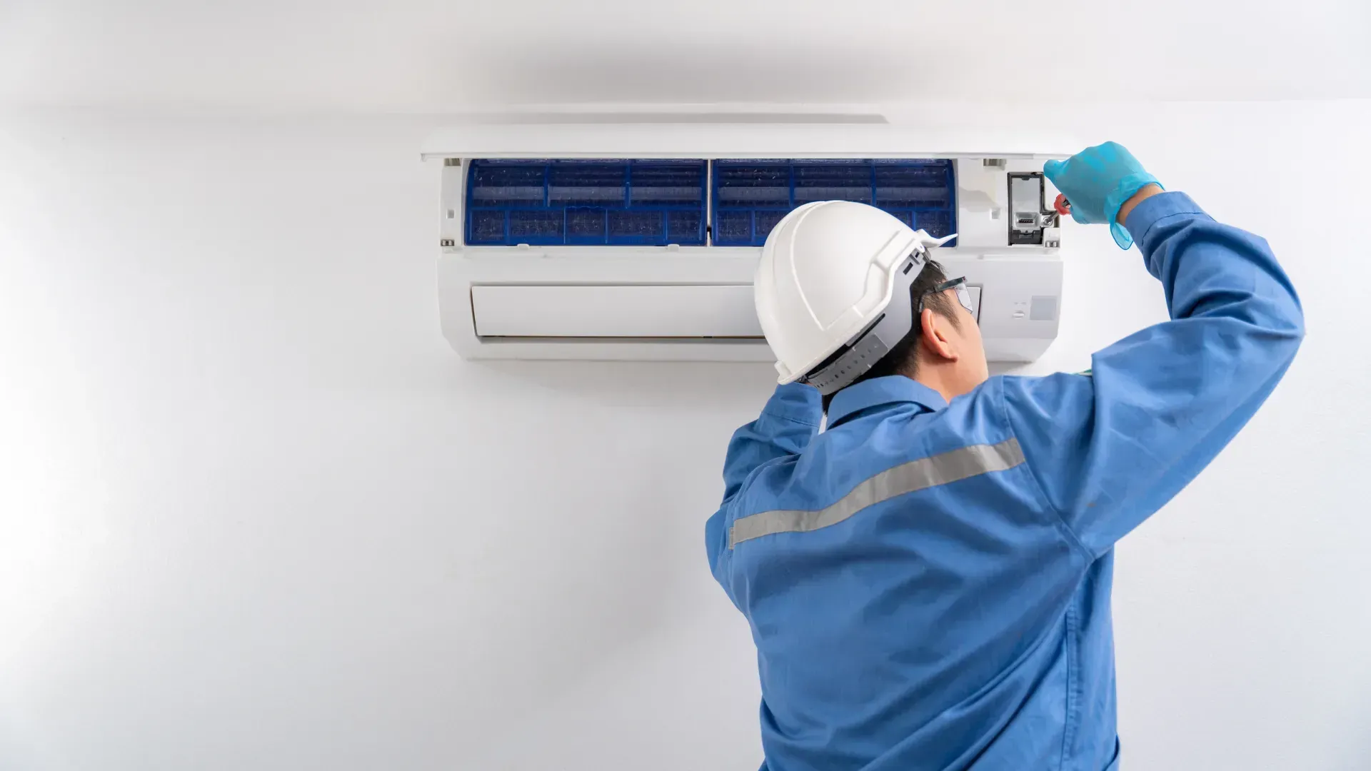 A man is working on an air conditioner in a room.
