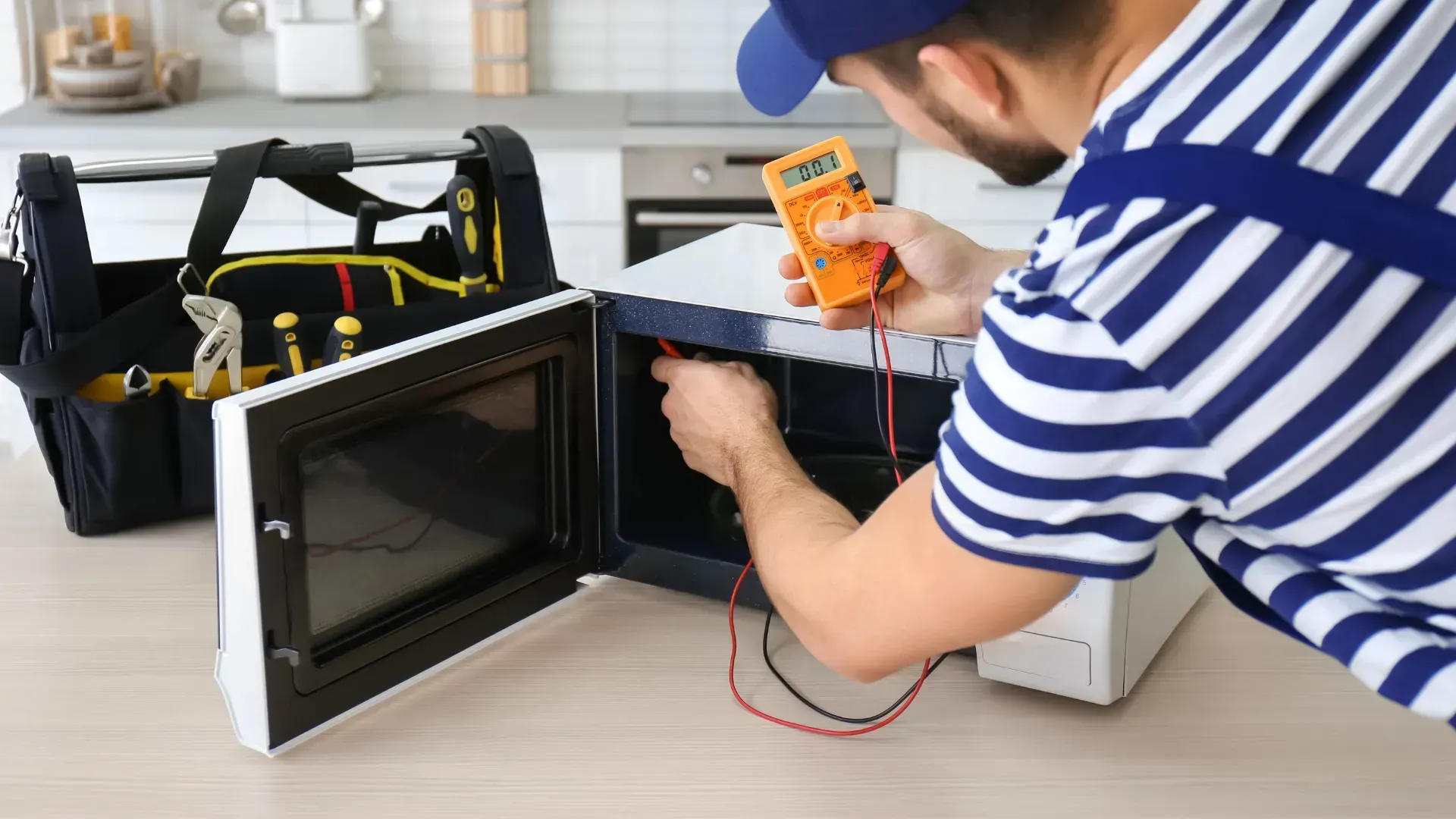 A man is fixing a microwave with a multimeter.