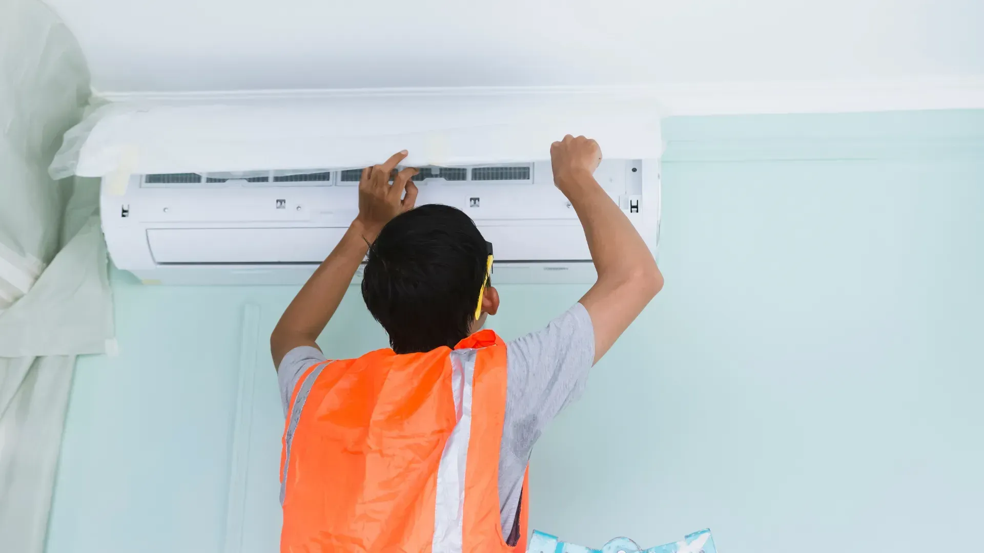 A man is installing an air conditioner in a room.