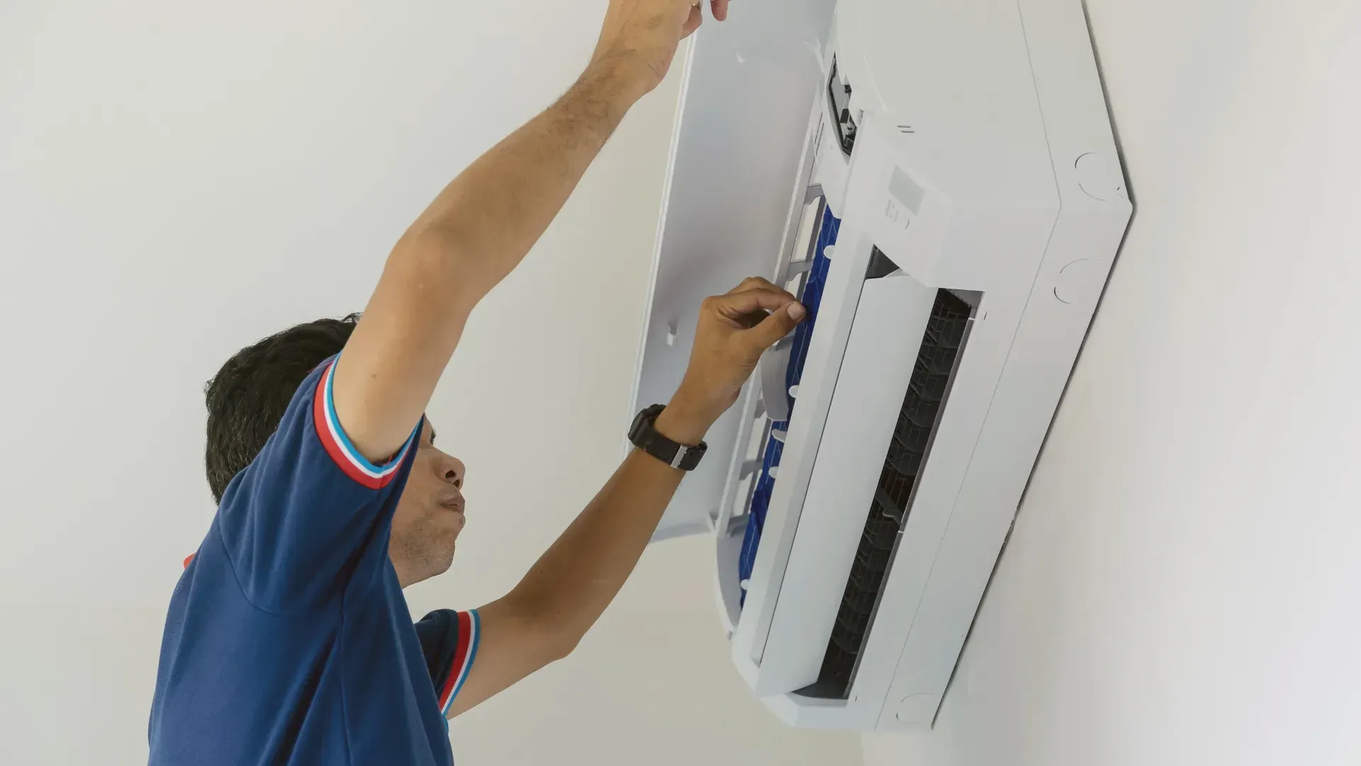A man is installing an air conditioner on a wall.