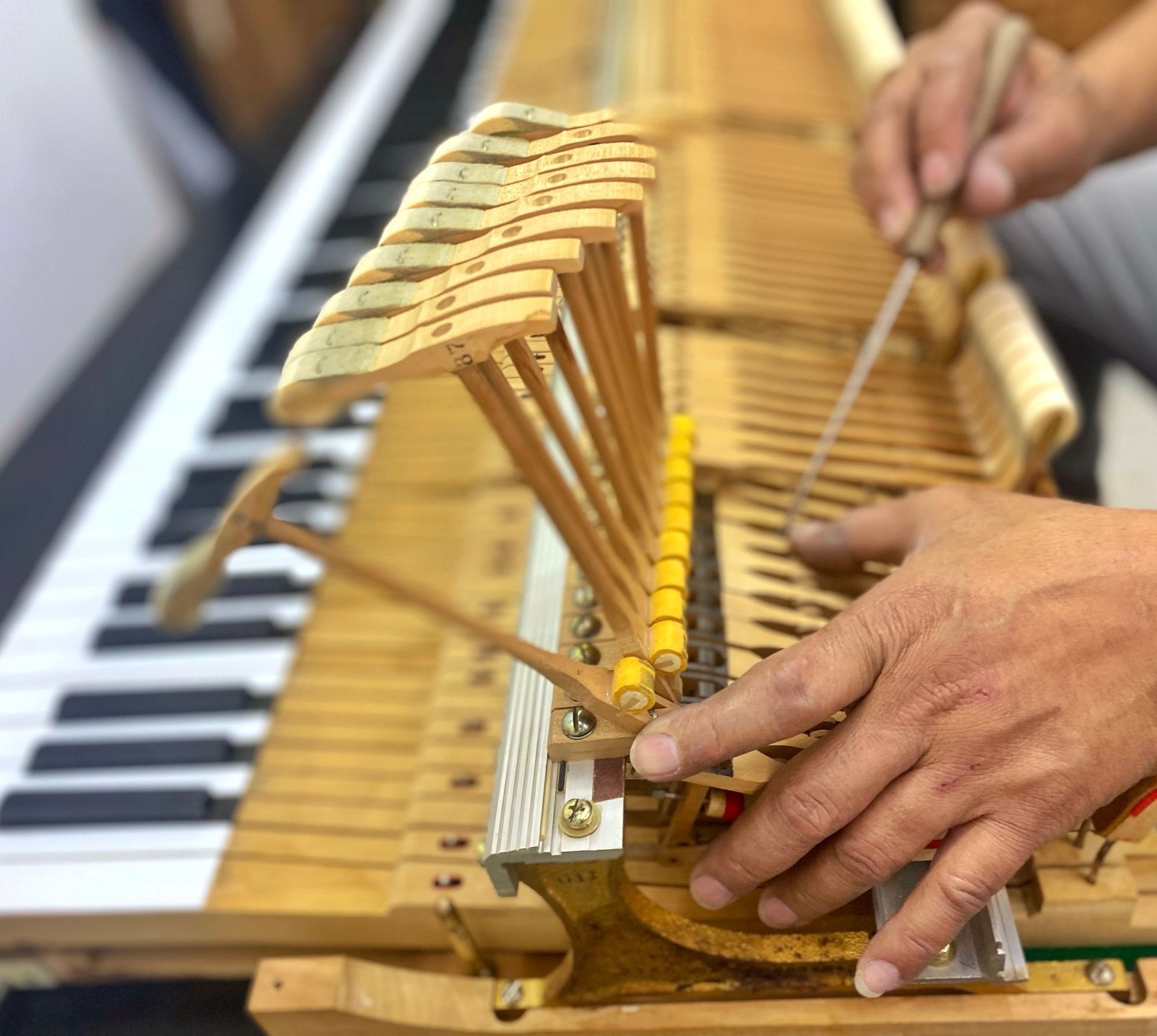 A person is working on a piano with a screwdriver