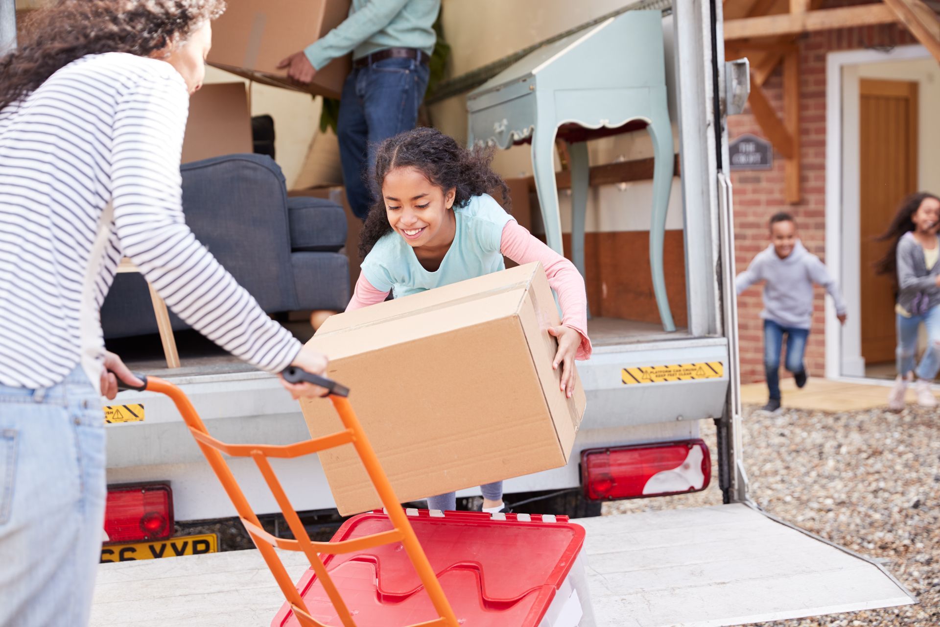 A woman is pushing a box on a dolly into a moving truck.