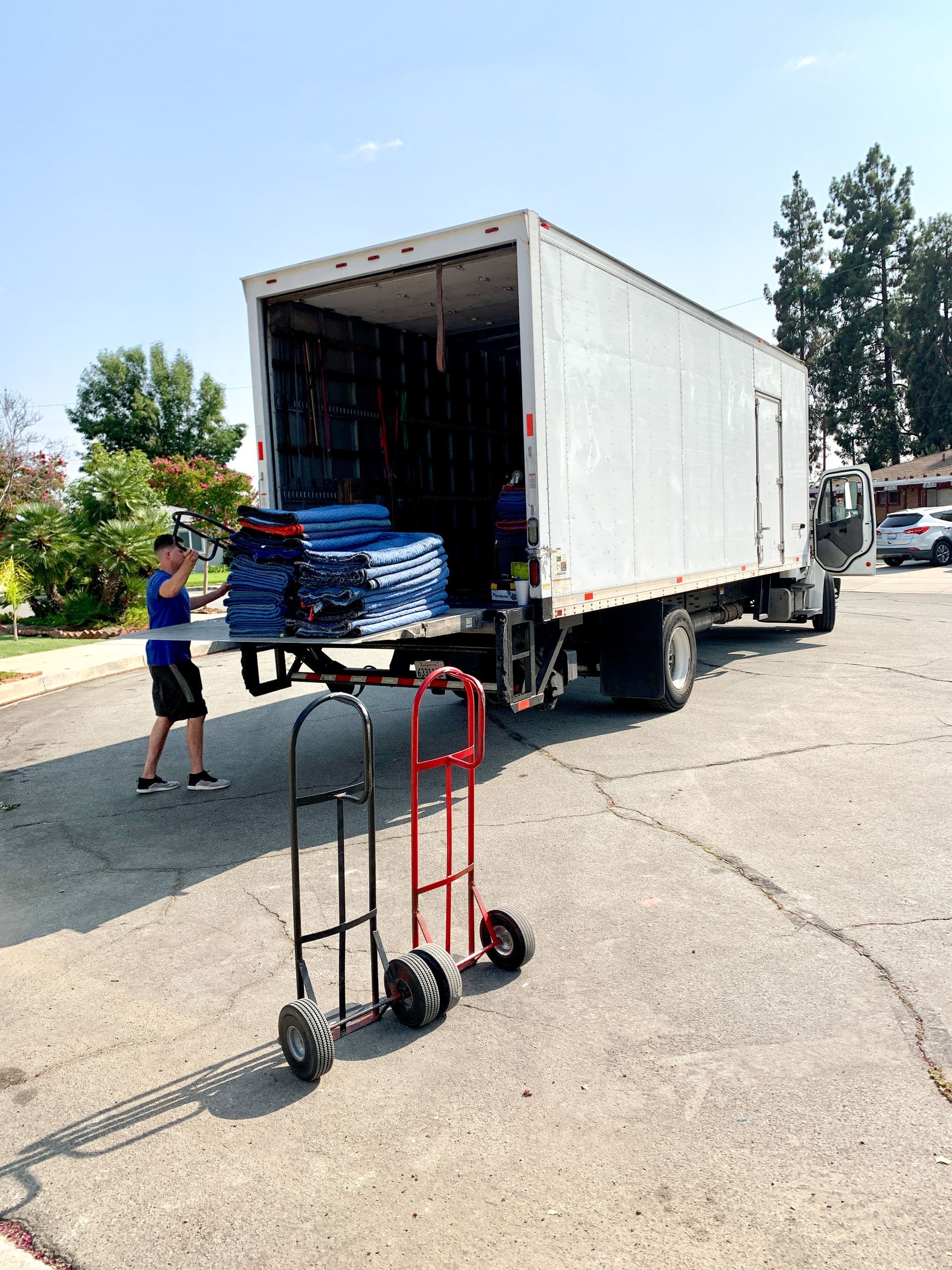 A man is pushing a dolly in front of a moving truck.