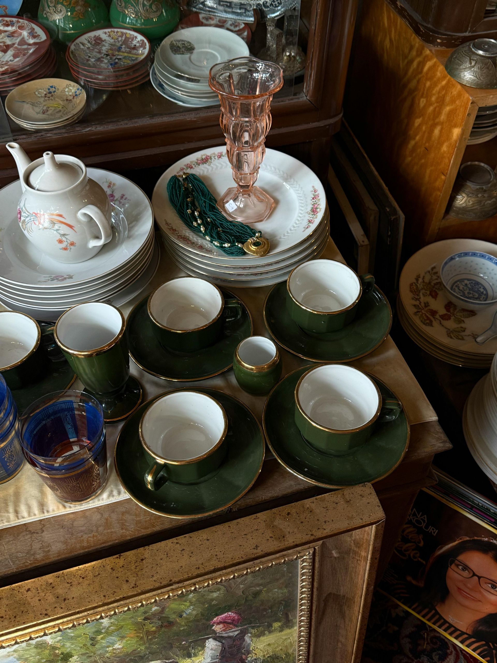 A table topped with plates , cups , saucers and a vase.