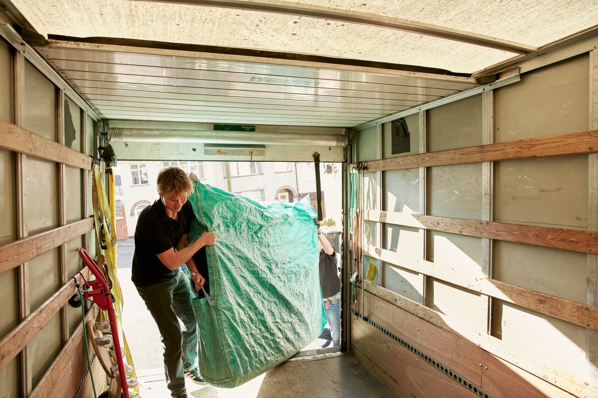 A man is carrying a piano in a moving truck.