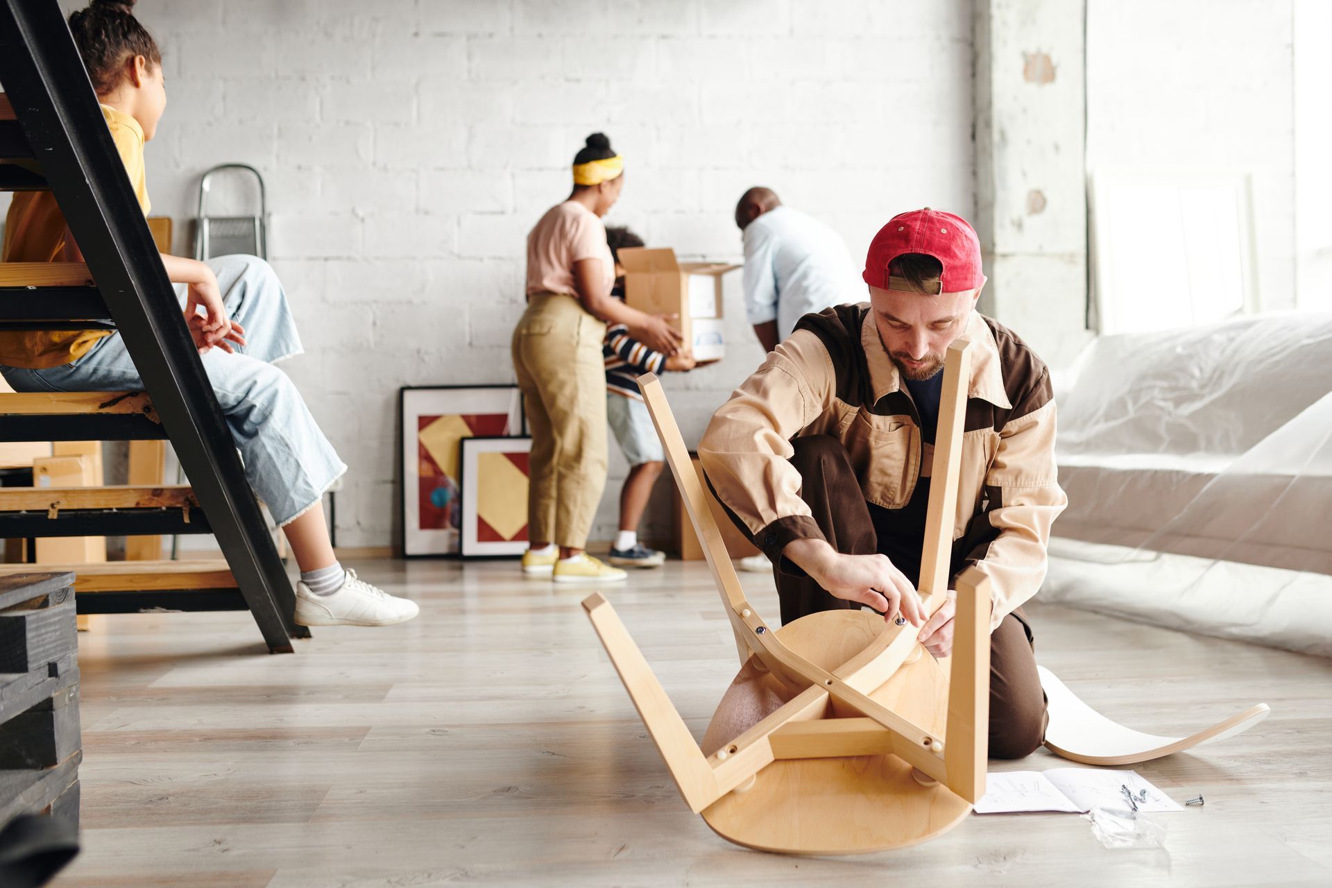 A man is kneeling on the floor assembling a wooden table.