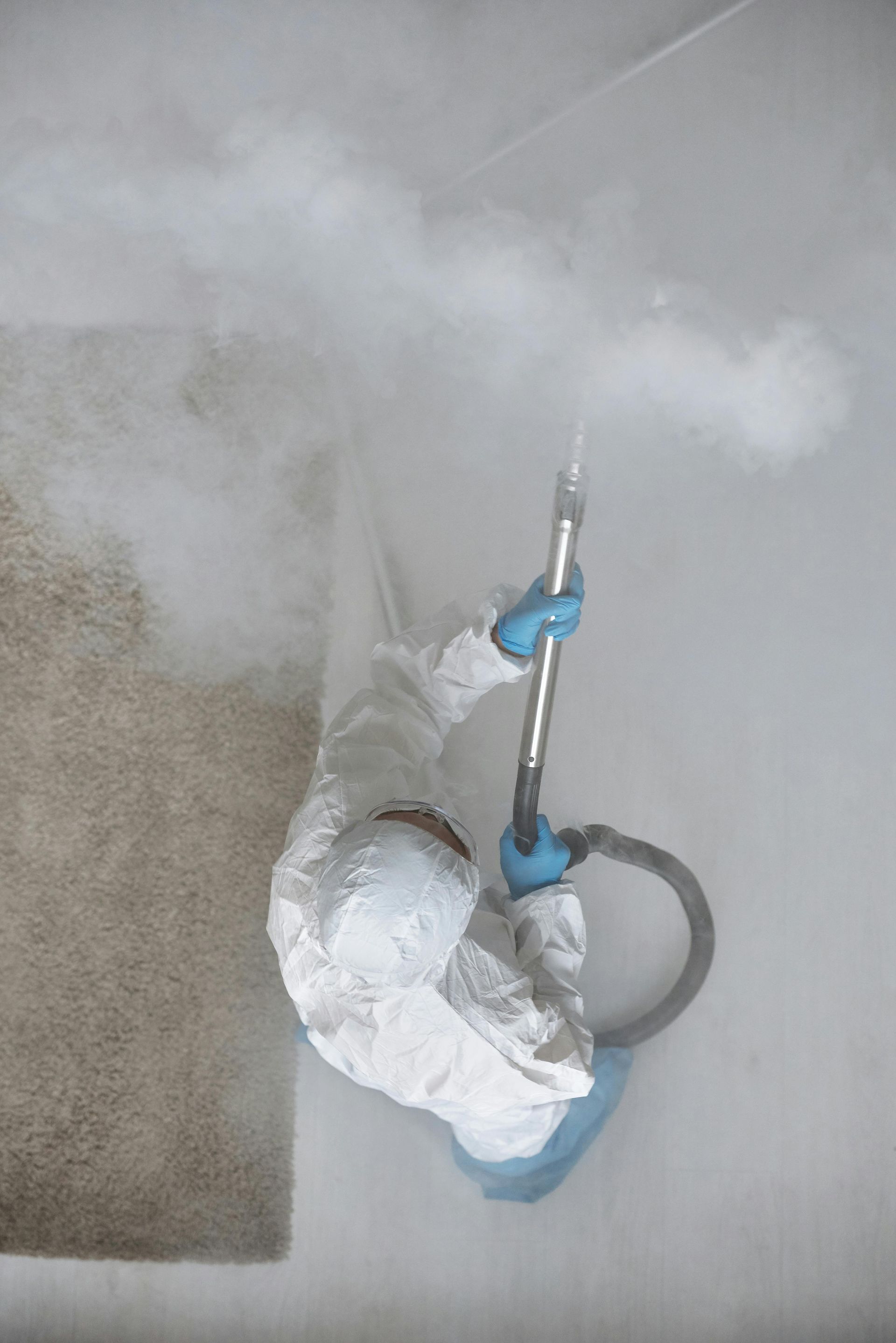 Person mopping a hardwood hallway floor in a bright home, with a blue bucket nearby.
