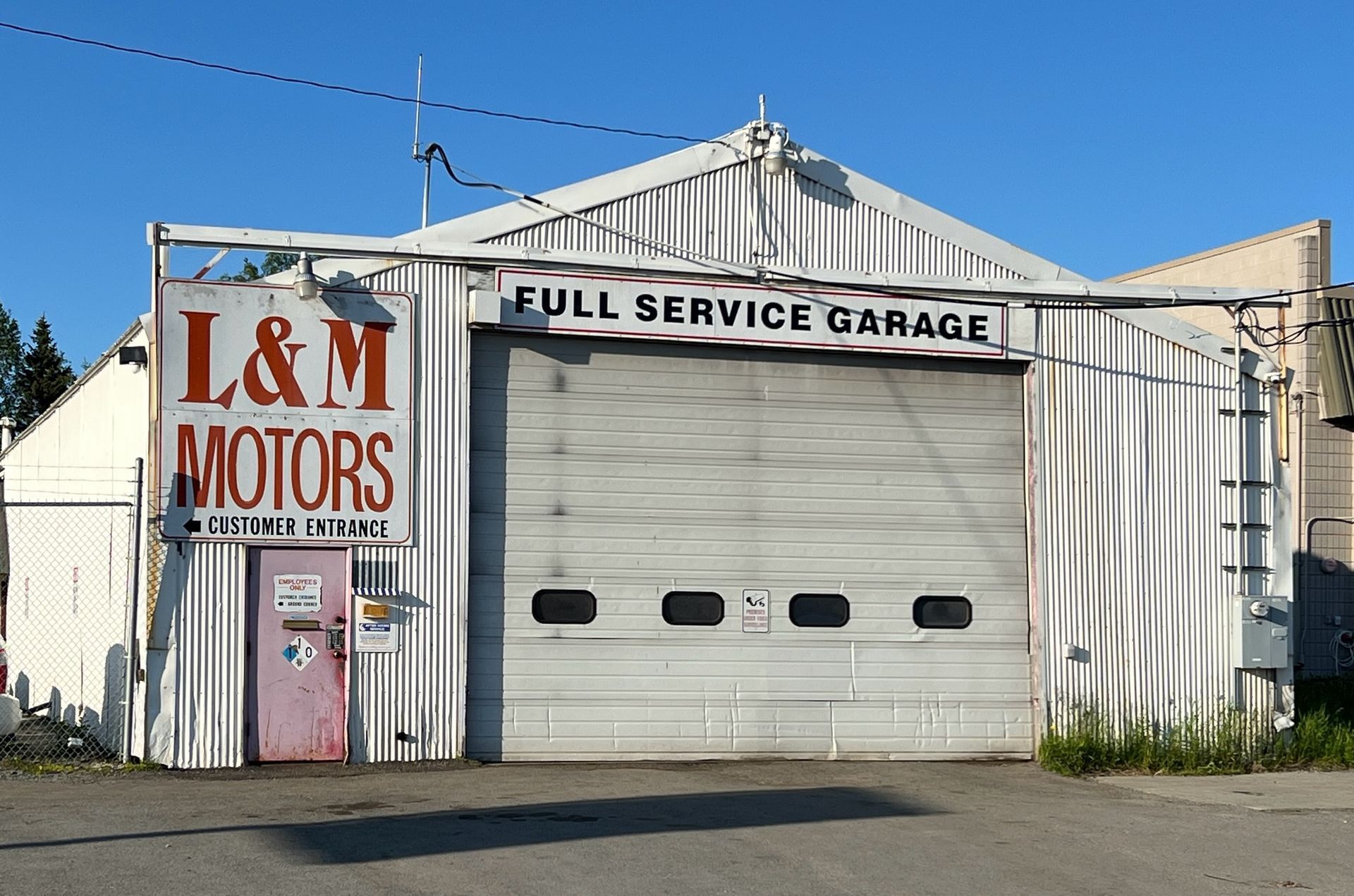 A white truck and a black suv are sitting on a lift in a garage.