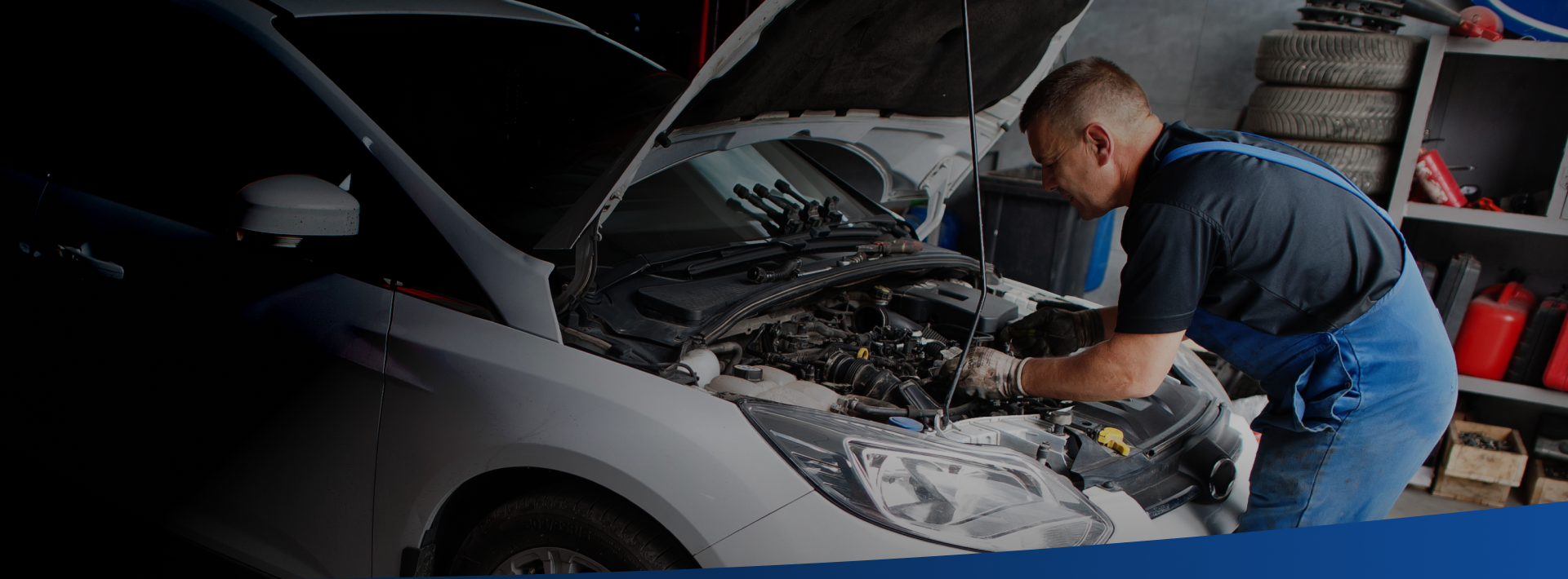 A man is working on the engine of a car in a garage.