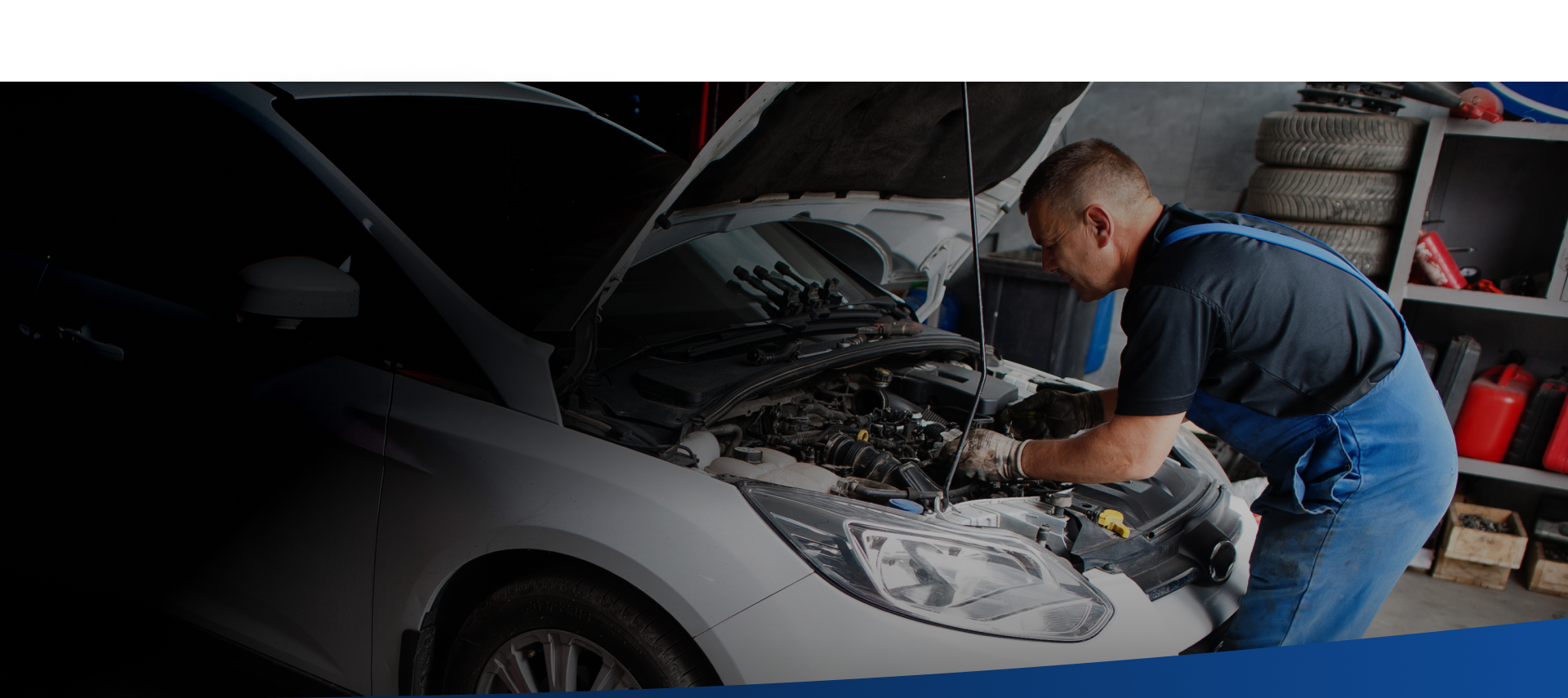 A man is working on the engine of a car in a garage.