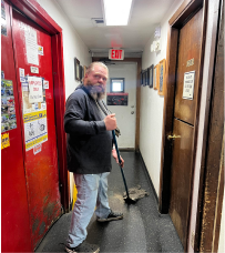 A man standing in a hallway with an exit sign above him