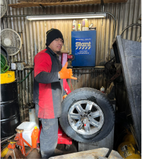A man is standing next to a tire in a garage.