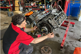 A man is working on a car engine in a garage.