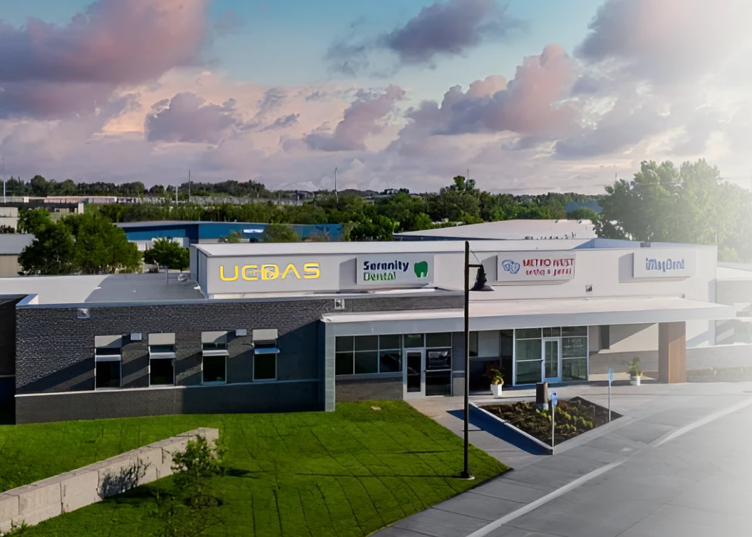 Modern commercial building with storefront signs, white and black exterior, under a cloudy sky