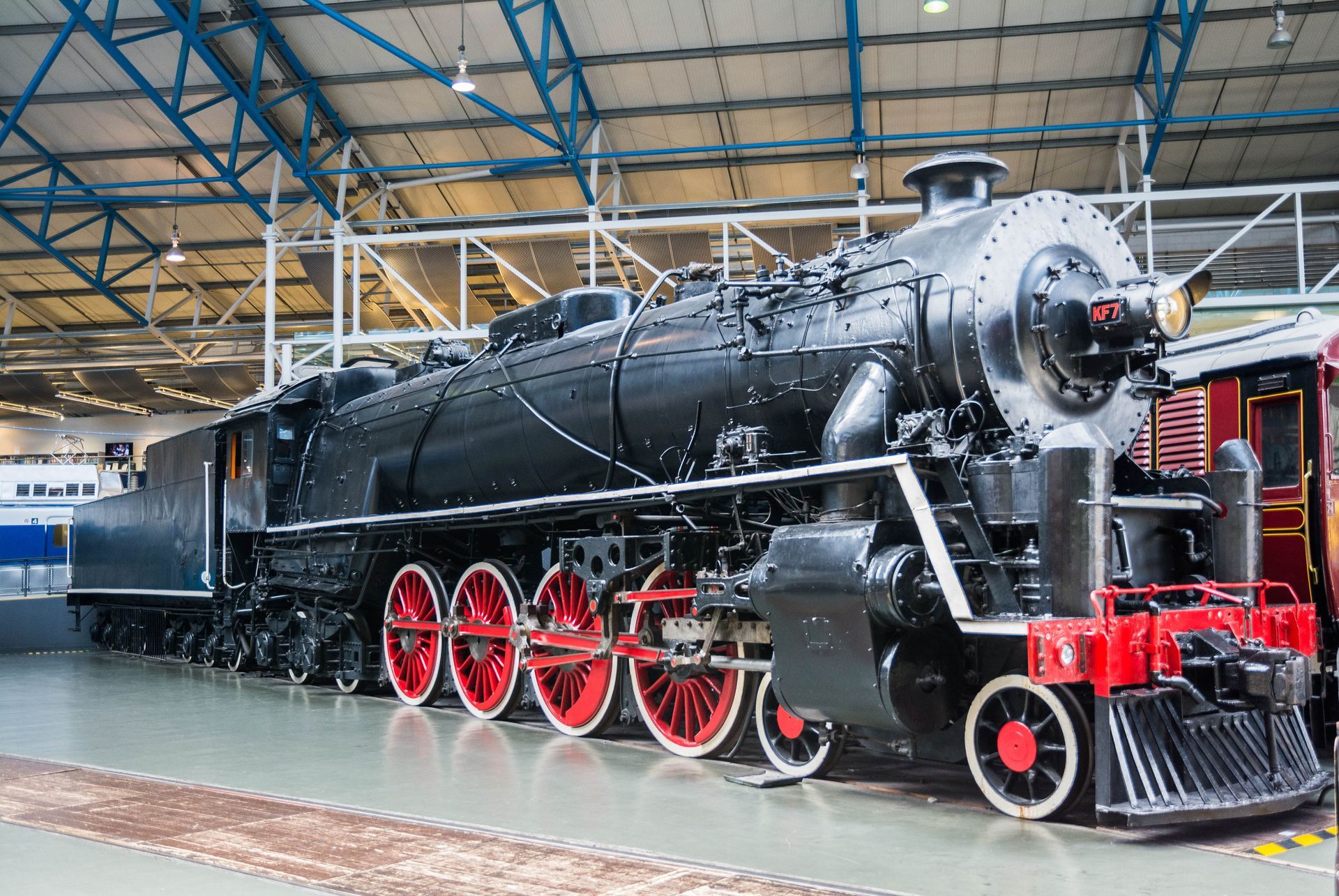 Black steam locomotive with red wheels and trim inside a building.