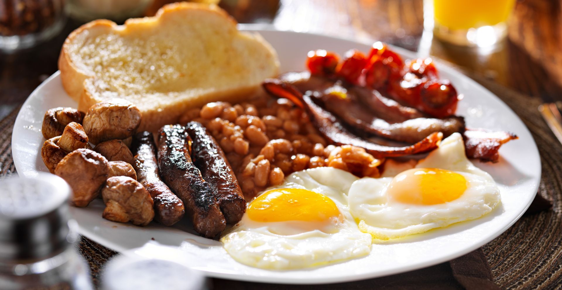 English breakfast: fried eggs, bacon, sausages, beans, mushrooms, tomatoes, toast.