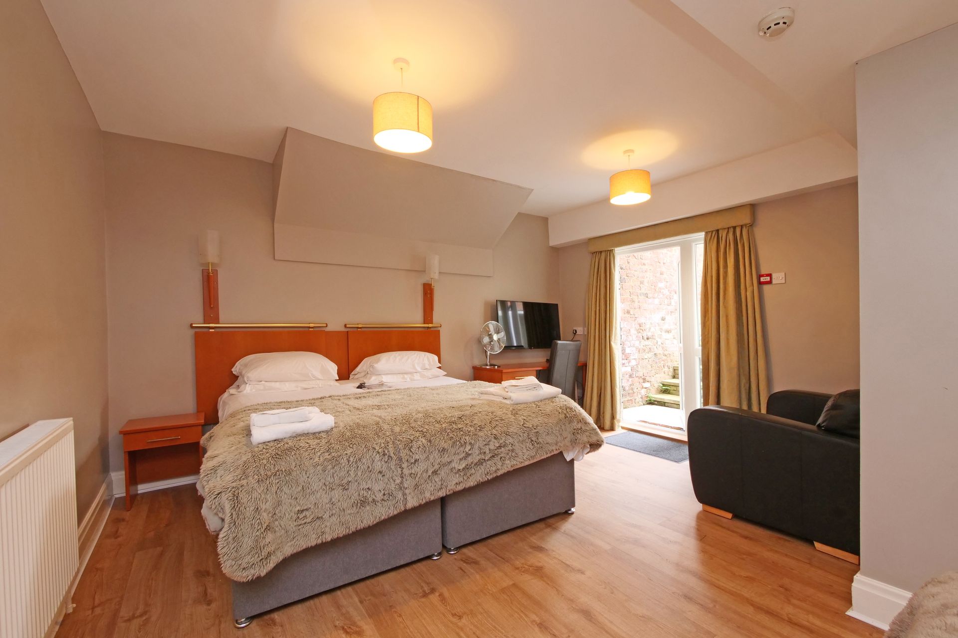 Hotel room with a double bed, small couch, and open doors to a patio.