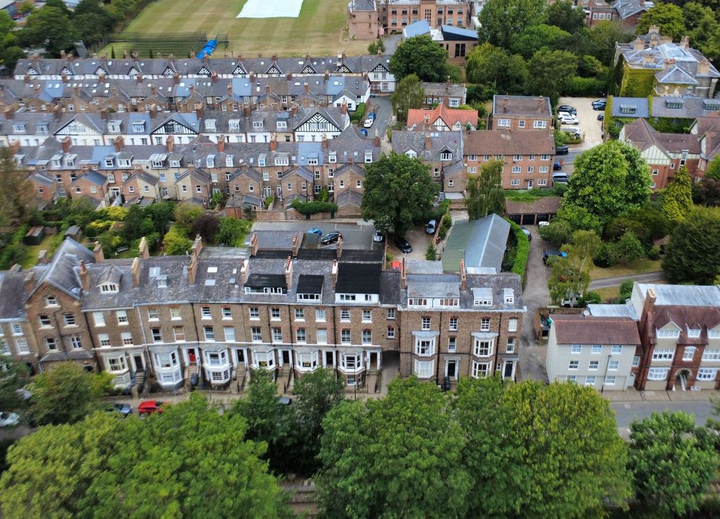 Aerial view of a residential area with rows of houses and green trees.