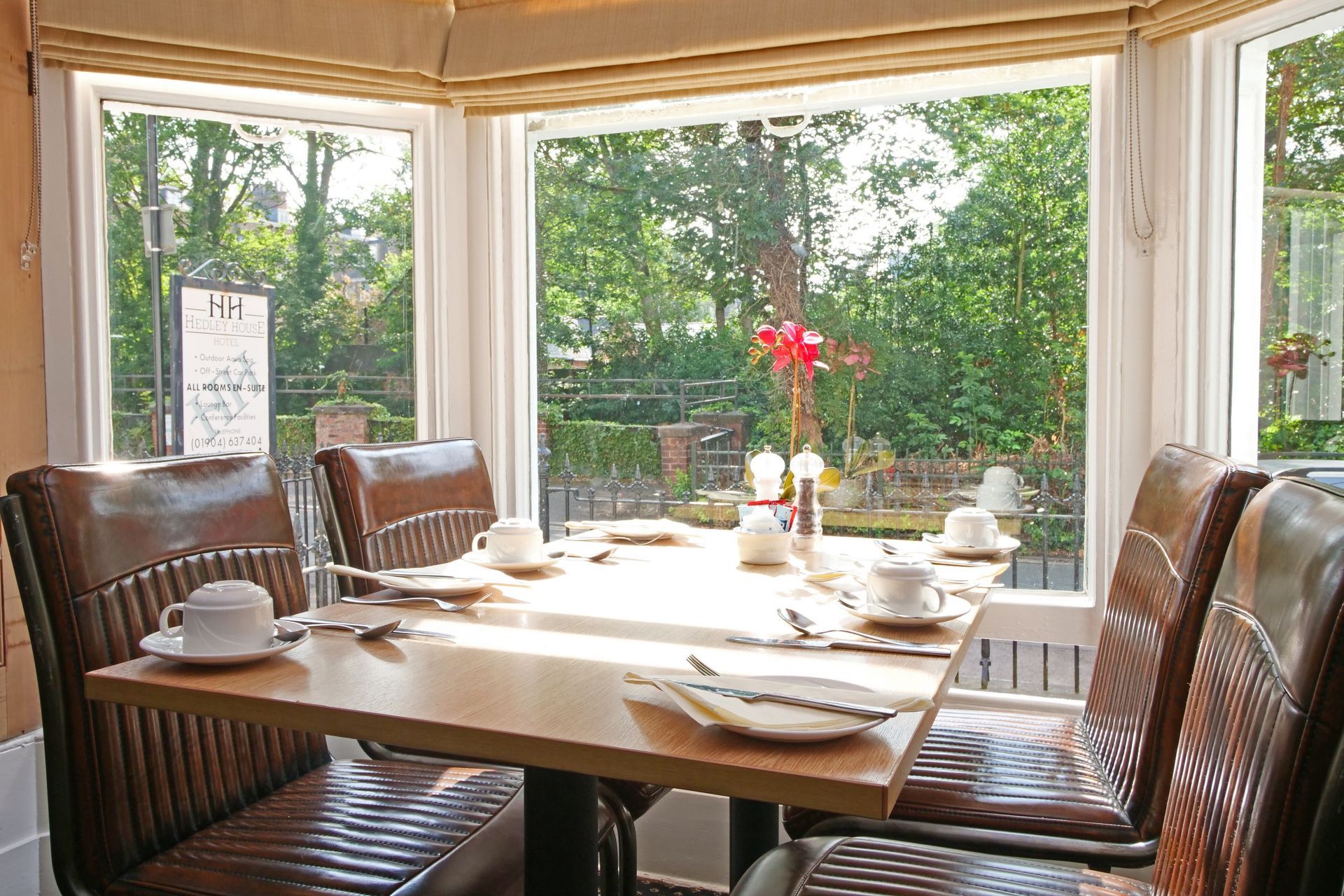 Breakfast table set for four by a large window overlooking a garden.