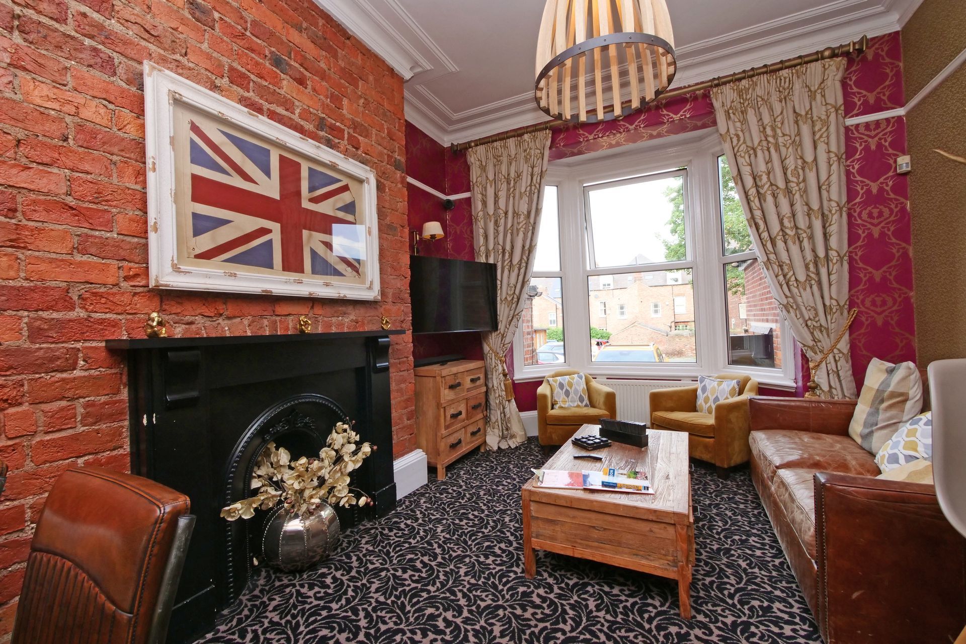 Living room with exposed brick, Union Jack art, sofa, armchairs, and coffee table.