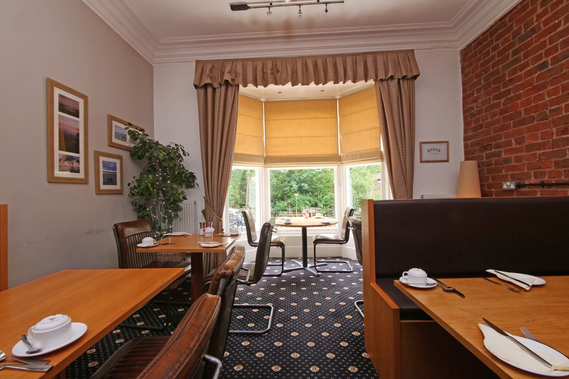 Breakfast room with tables, chairs, bay window, and exposed brick wall.
