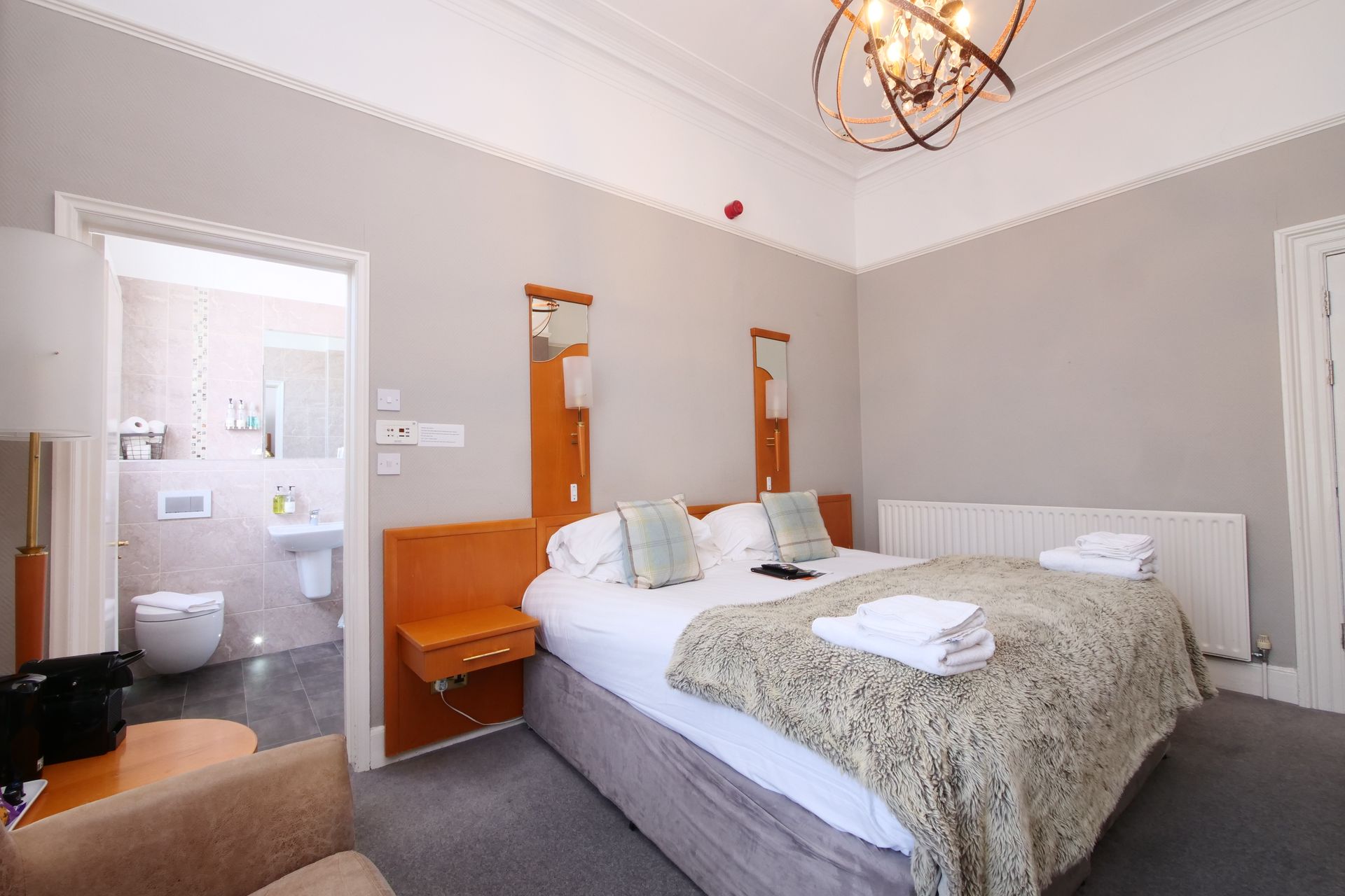 Hotel bedroom with a double bed, bathroom visible through the doorway, neutral colors.