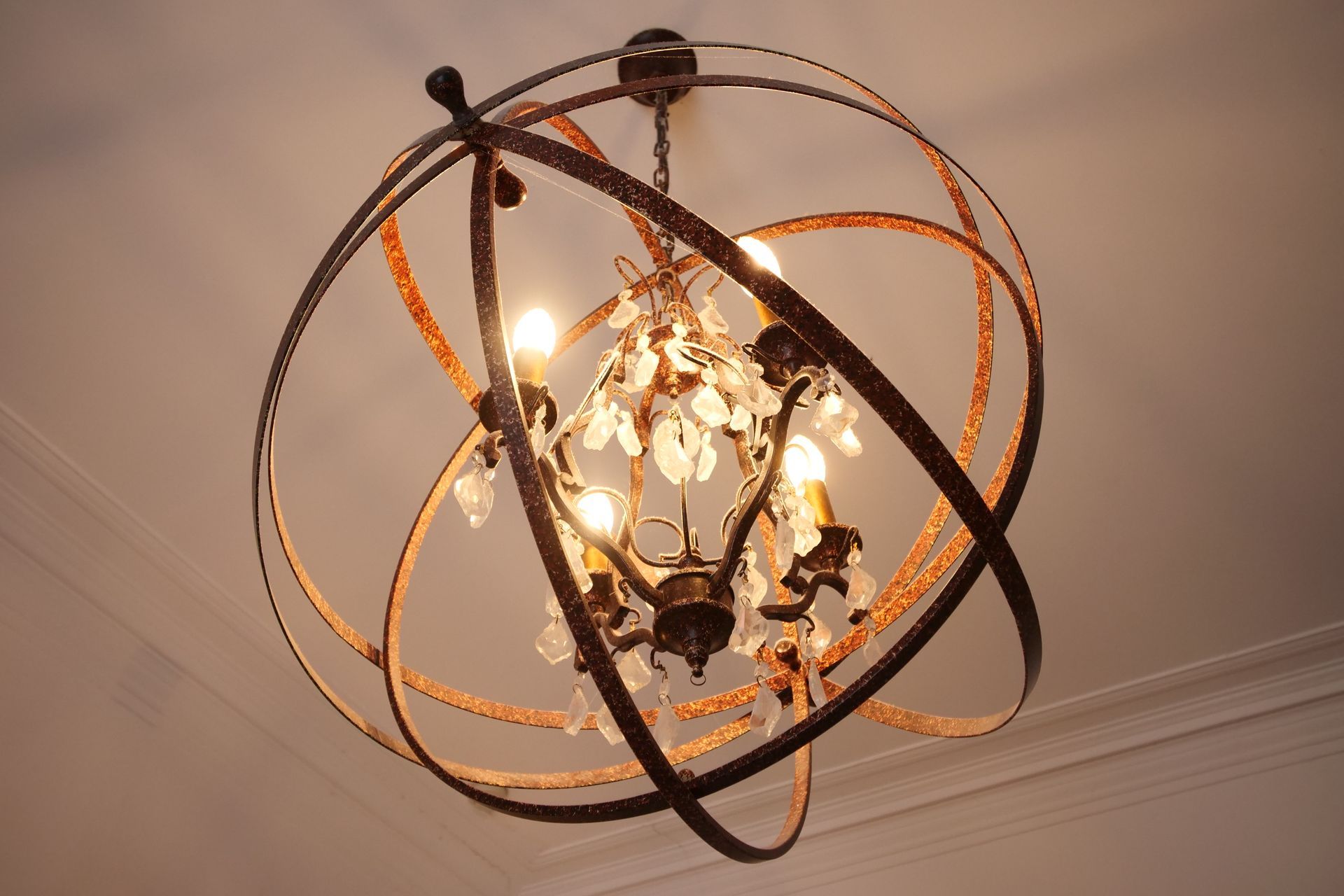 Bronze orb chandelier with crystal accents against a white ceiling.