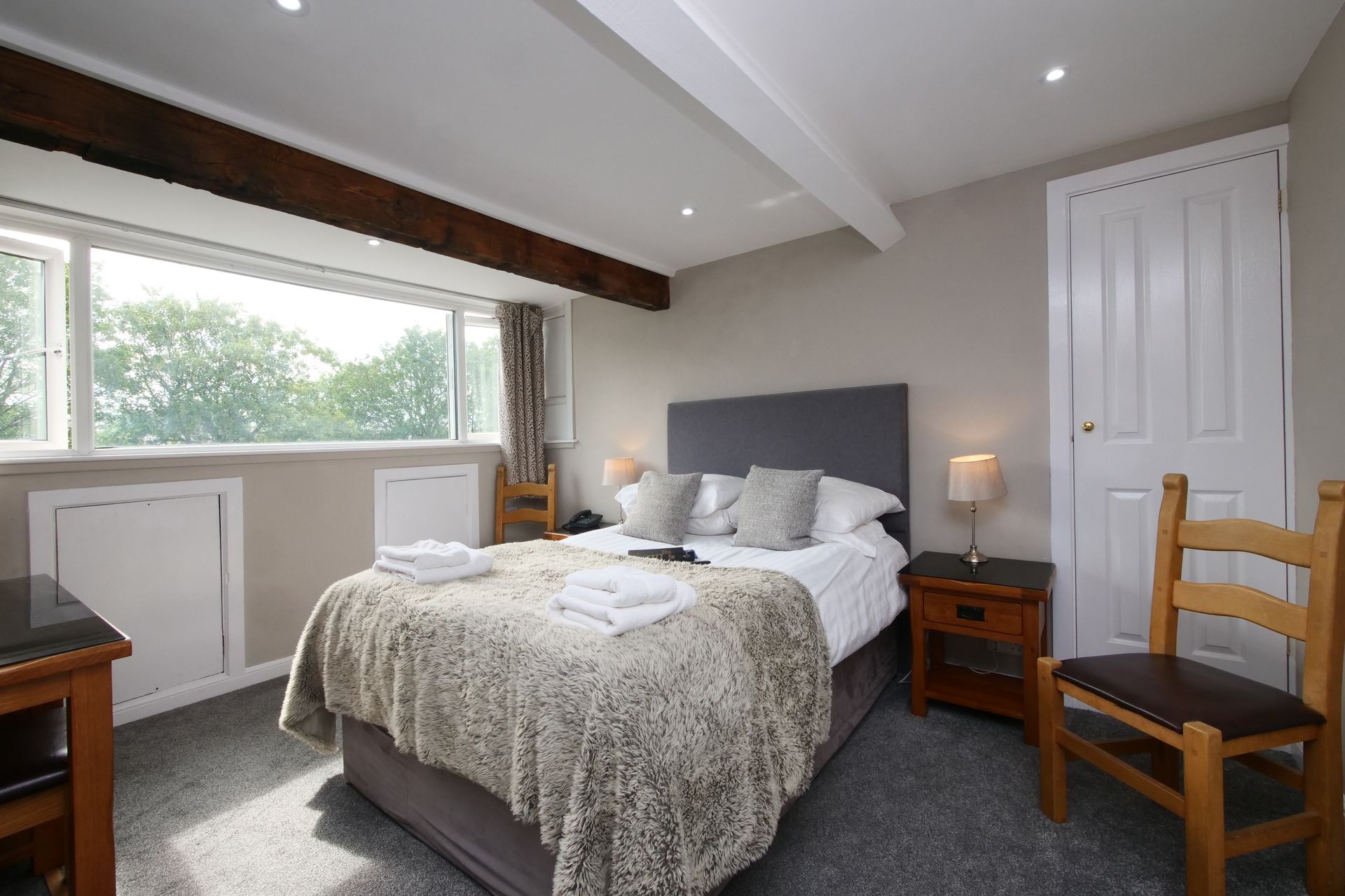 Bedroom with a bed, window, wooden furniture, and neutral color scheme.