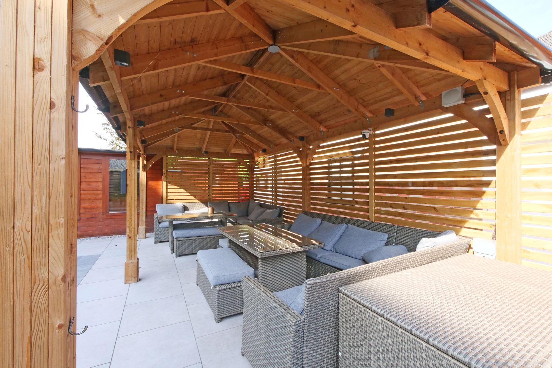 Wooden gazebo with outdoor seating and tables.