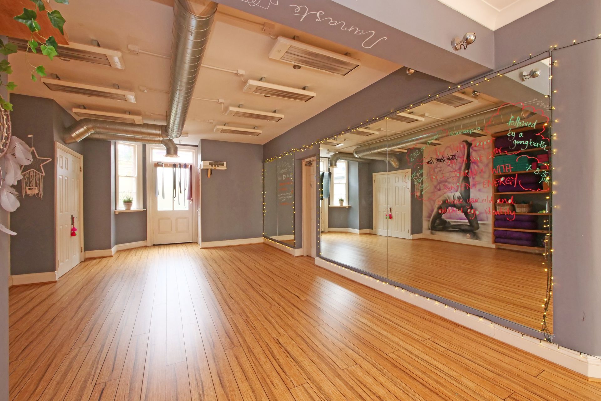 Dance studio with wood floor, mirrors, grey walls, and an Eiffel Tower mural.