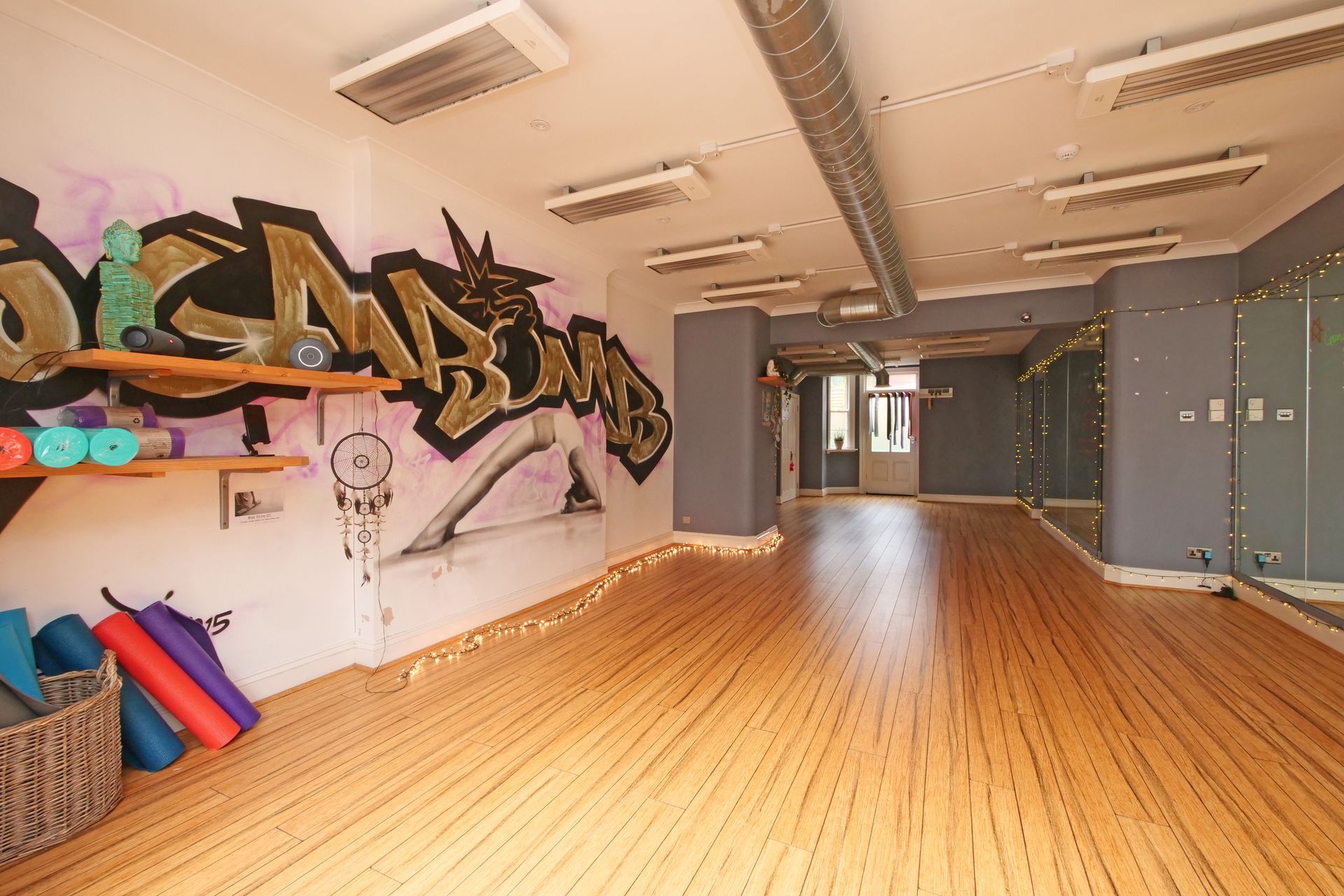 Empty yoga studio with graffiti wall and wooden floor.
