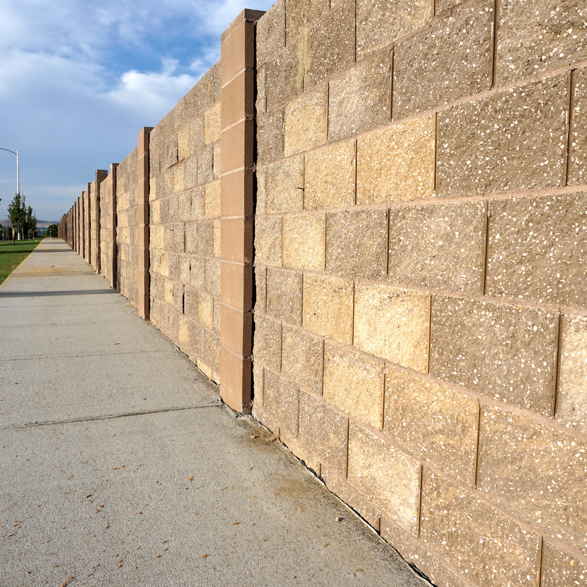 A brick wall with a sidewalk in front of it