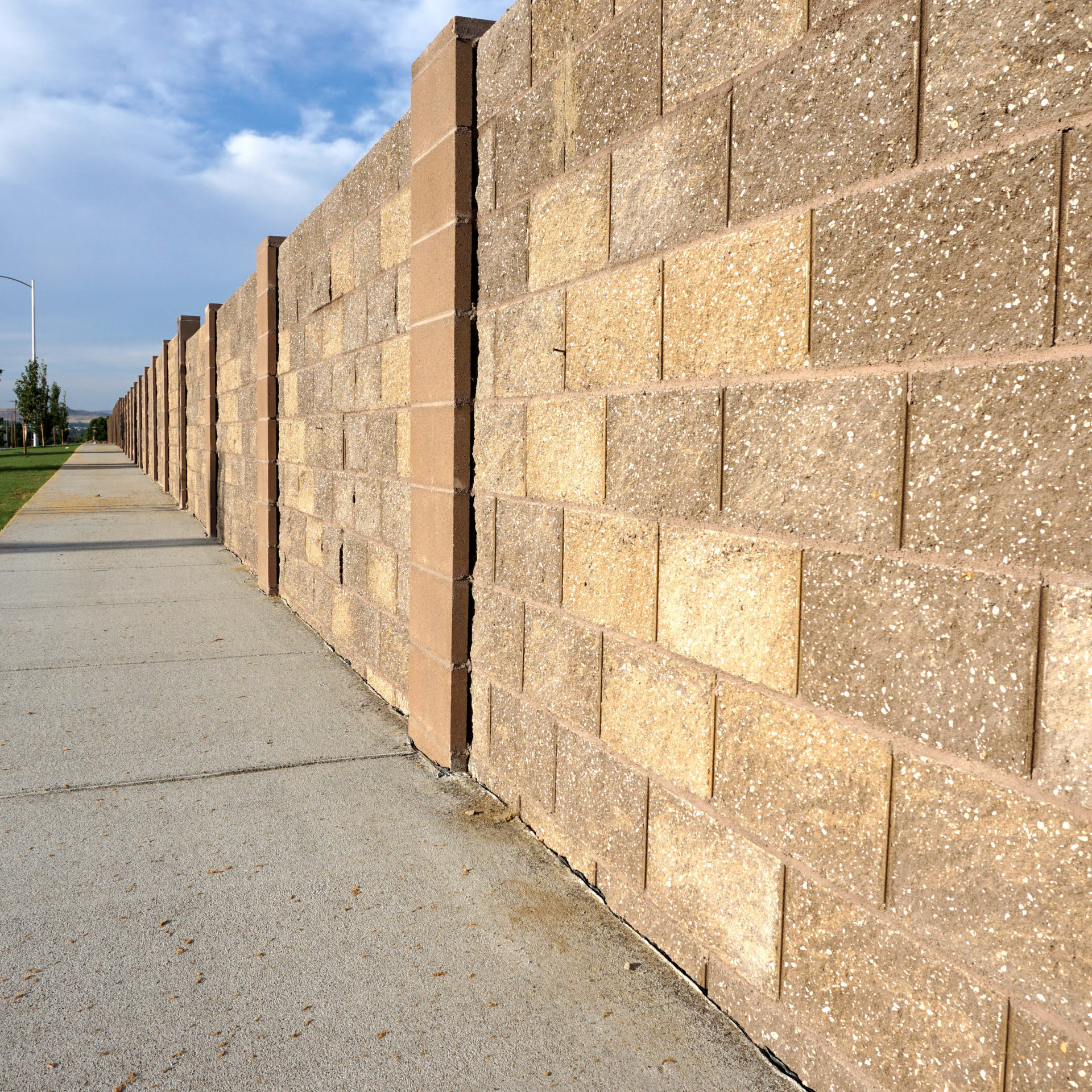 A brick wall with a sidewalk in front of it