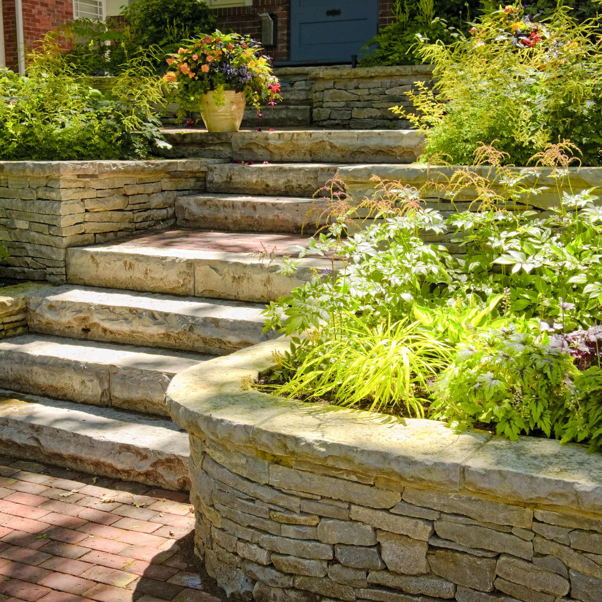 A stone wall surrounds a set of stairs leading up to a house