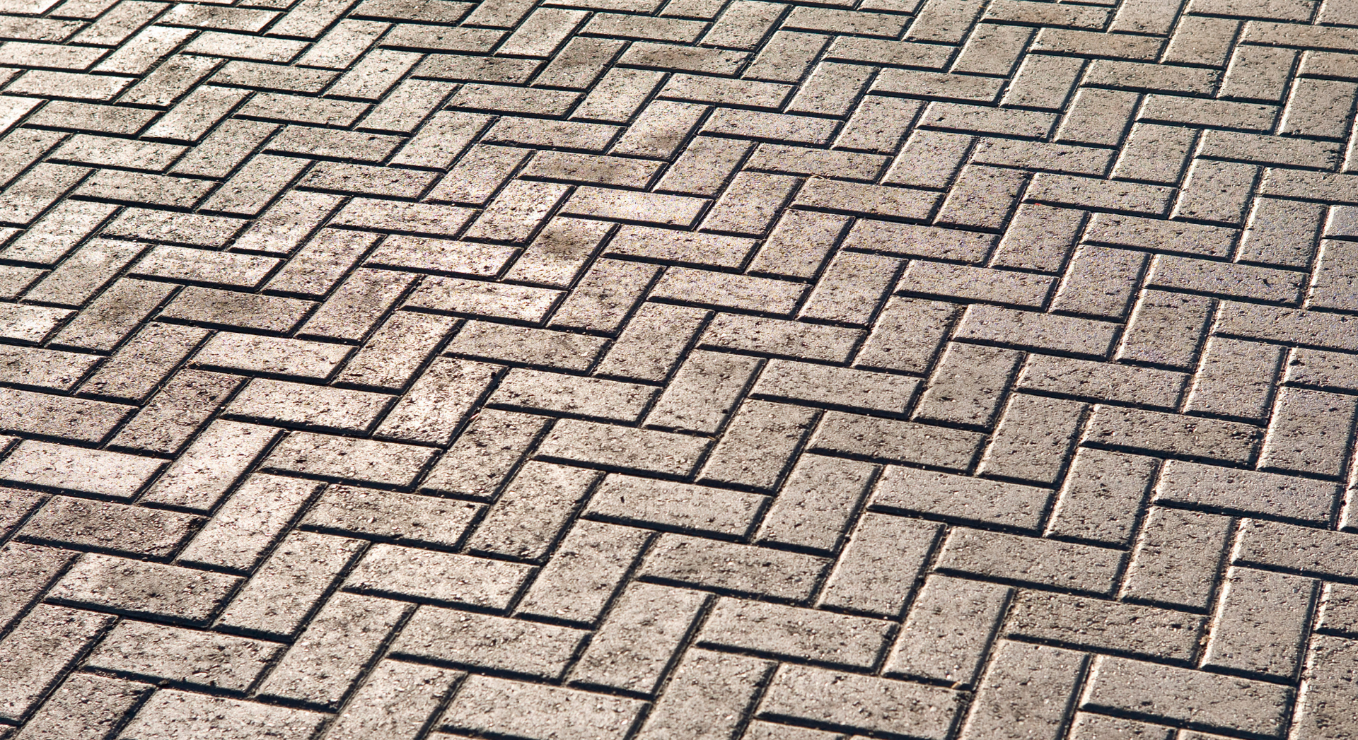 A close up of a brick pavement with a herringbone pattern.