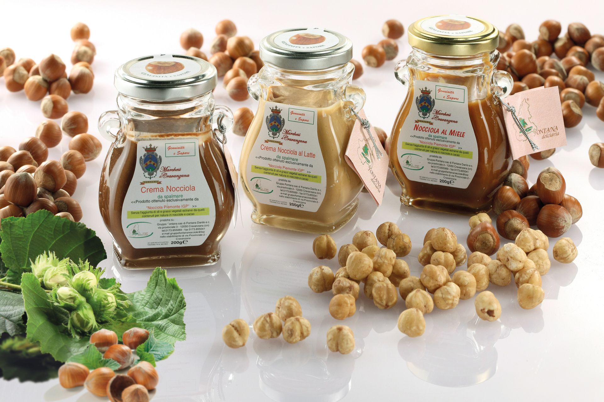 Tre barattoli di crema di nocciole con noci sparse.